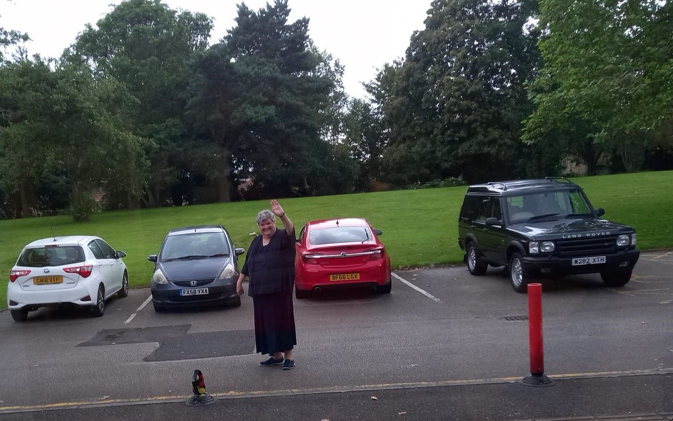 A woman stands in a parking lot with cars parked behind her