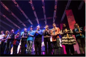 a group of people are standing on a stage holding crosses .