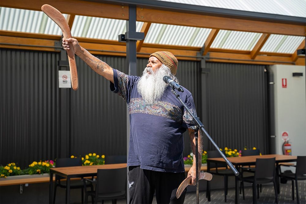 A man with a beard is holding a boomerang in front of a microphone.
