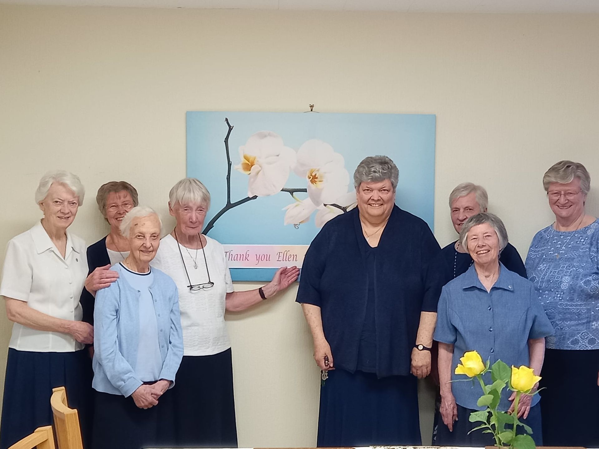 A group of people standing in front of a painting of flowers