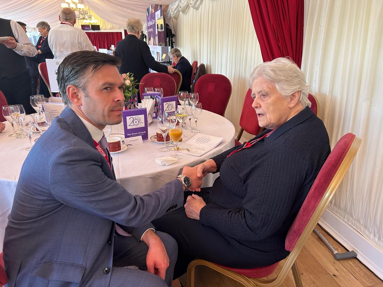 A man and a woman are sitting at a table talking to each other.