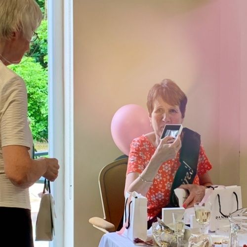 A woman is taking a picture of another woman sitting at a table