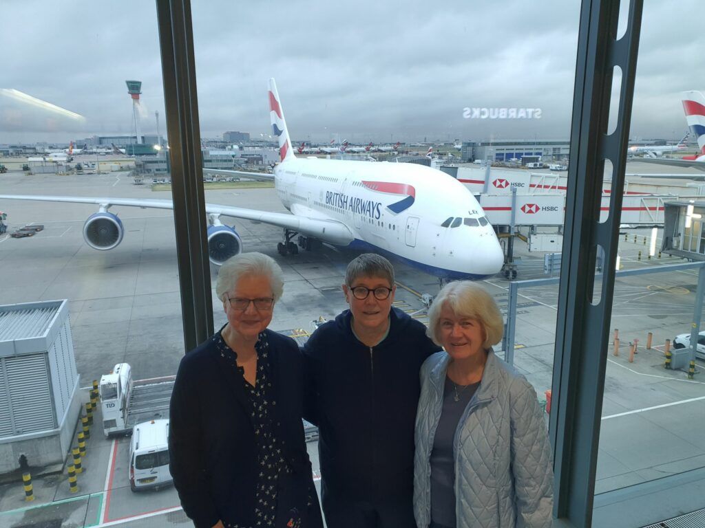 Three people are posing for a picture in front of an airplane.