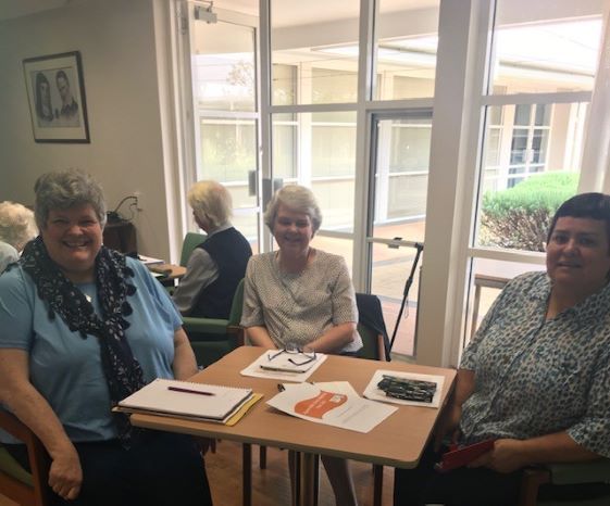 A group of women are sitting at a table with papers on it