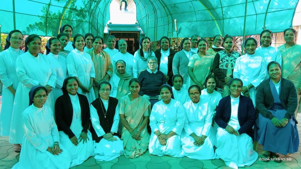 Group of women, likely nuns, in white and blue robes, posing outdoors.
