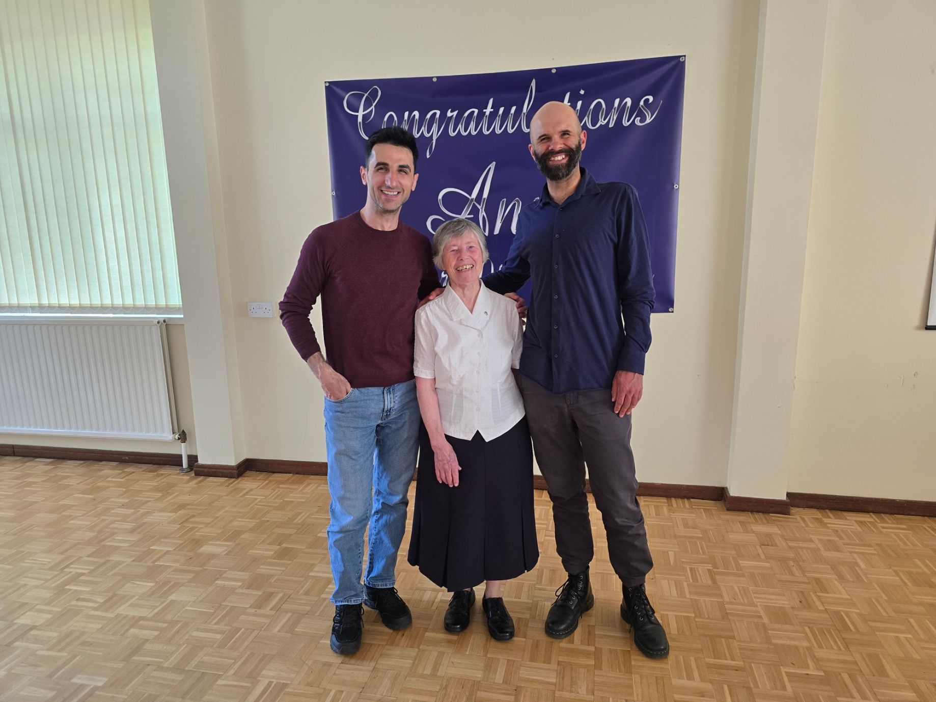 Three people smiling in front of a blue