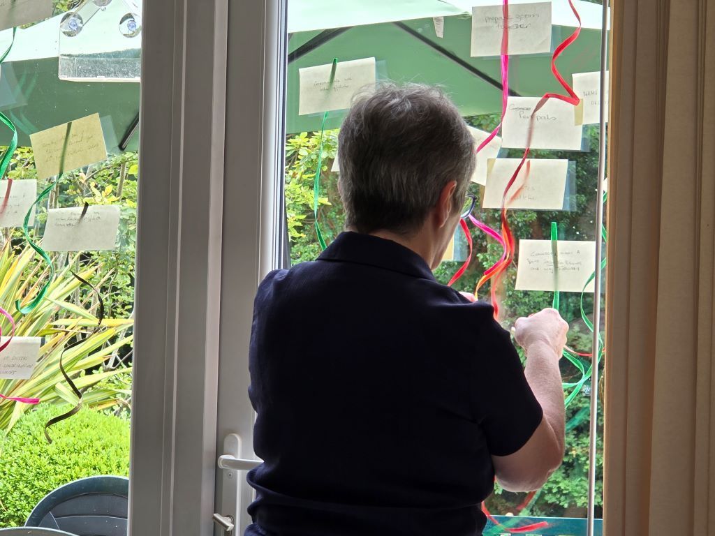 A man is standing in front of a window with sticky notes on it.