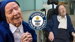 An elderly woman is sitting in a wheelchair next to a guinness world records logo.