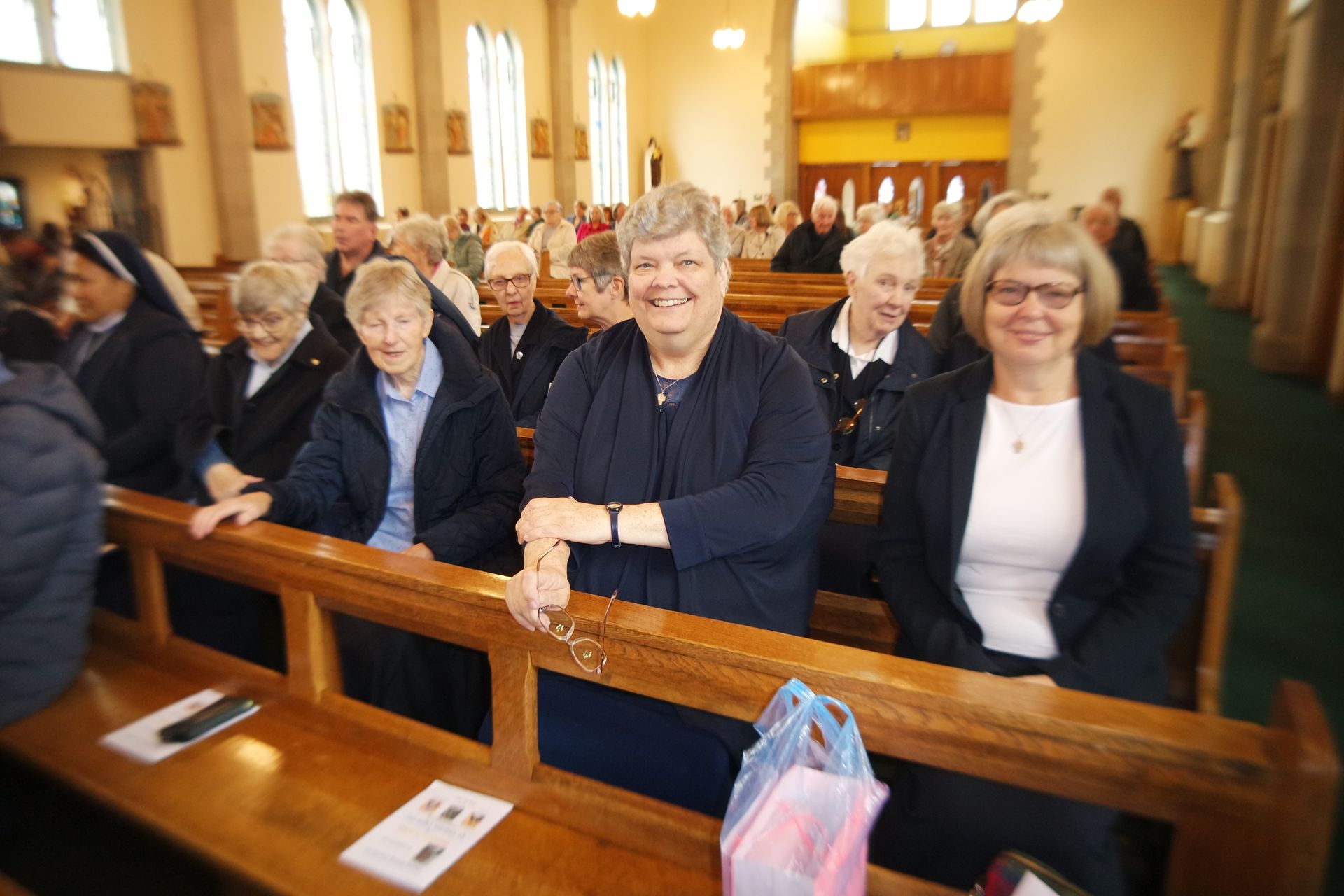 A group of people are sitting on benches in a church.