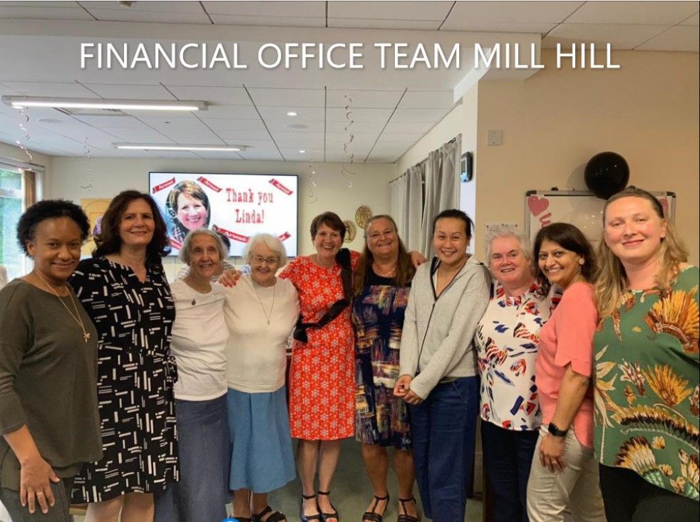 A group of women are posing for a picture and the caption says financial office team mill hill
