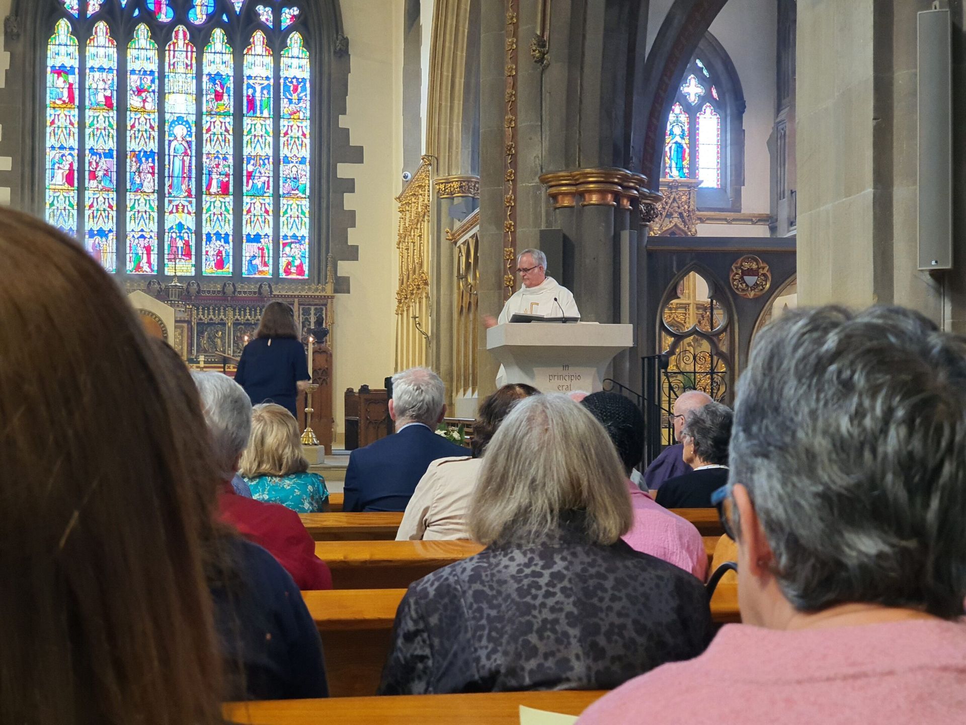 A group of people are sitting in a church with stained glass windows