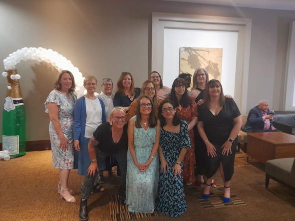 A group of women are posing for a picture in a room.