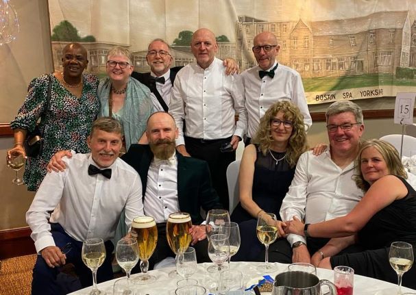 A group of people are posing for a picture at a table with wine glasses.
