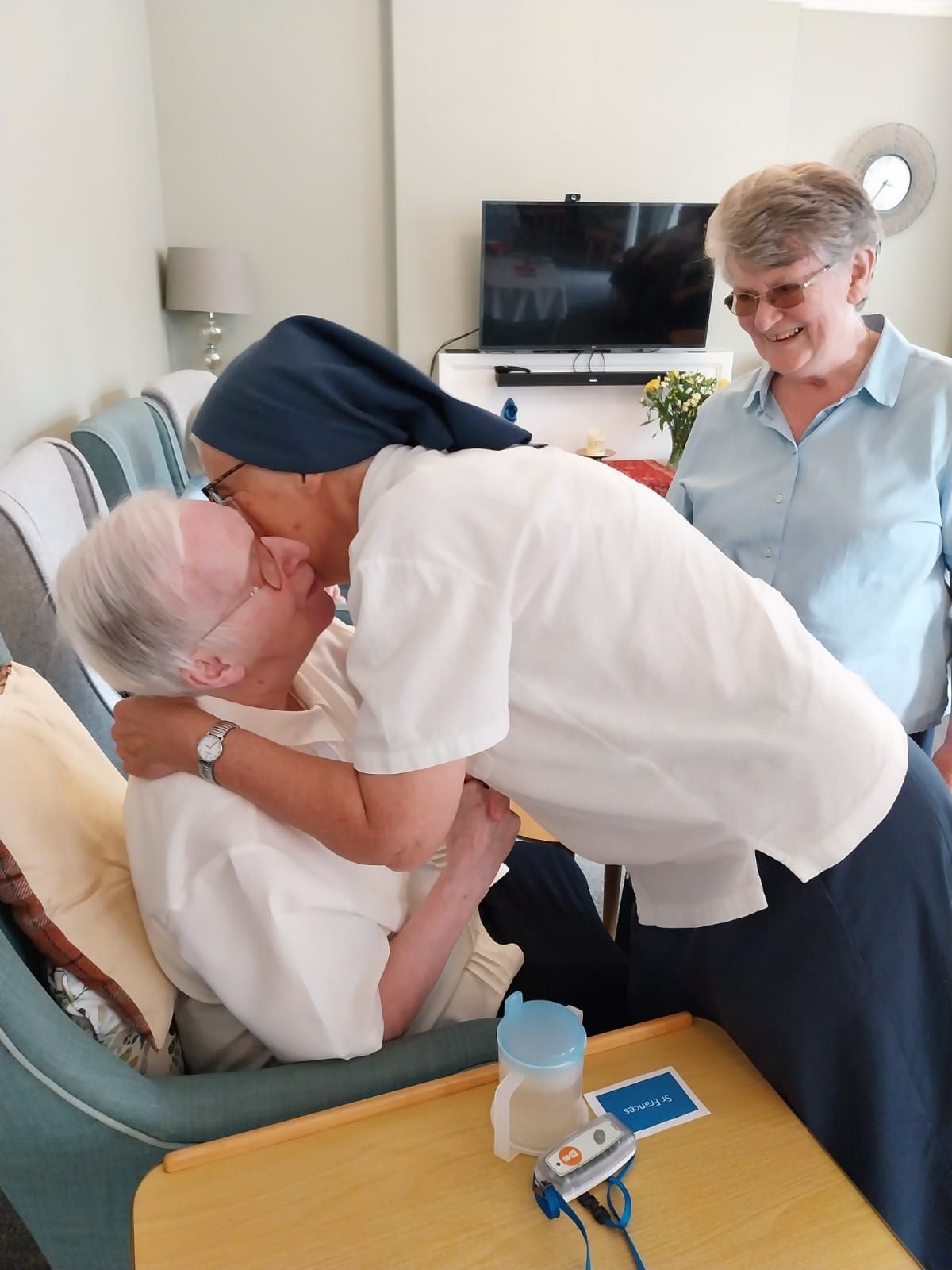 A woman is kissing an elderly woman in a living room