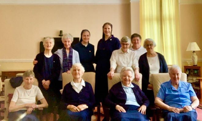 A group of elderly women are posing for a picture in a living room.