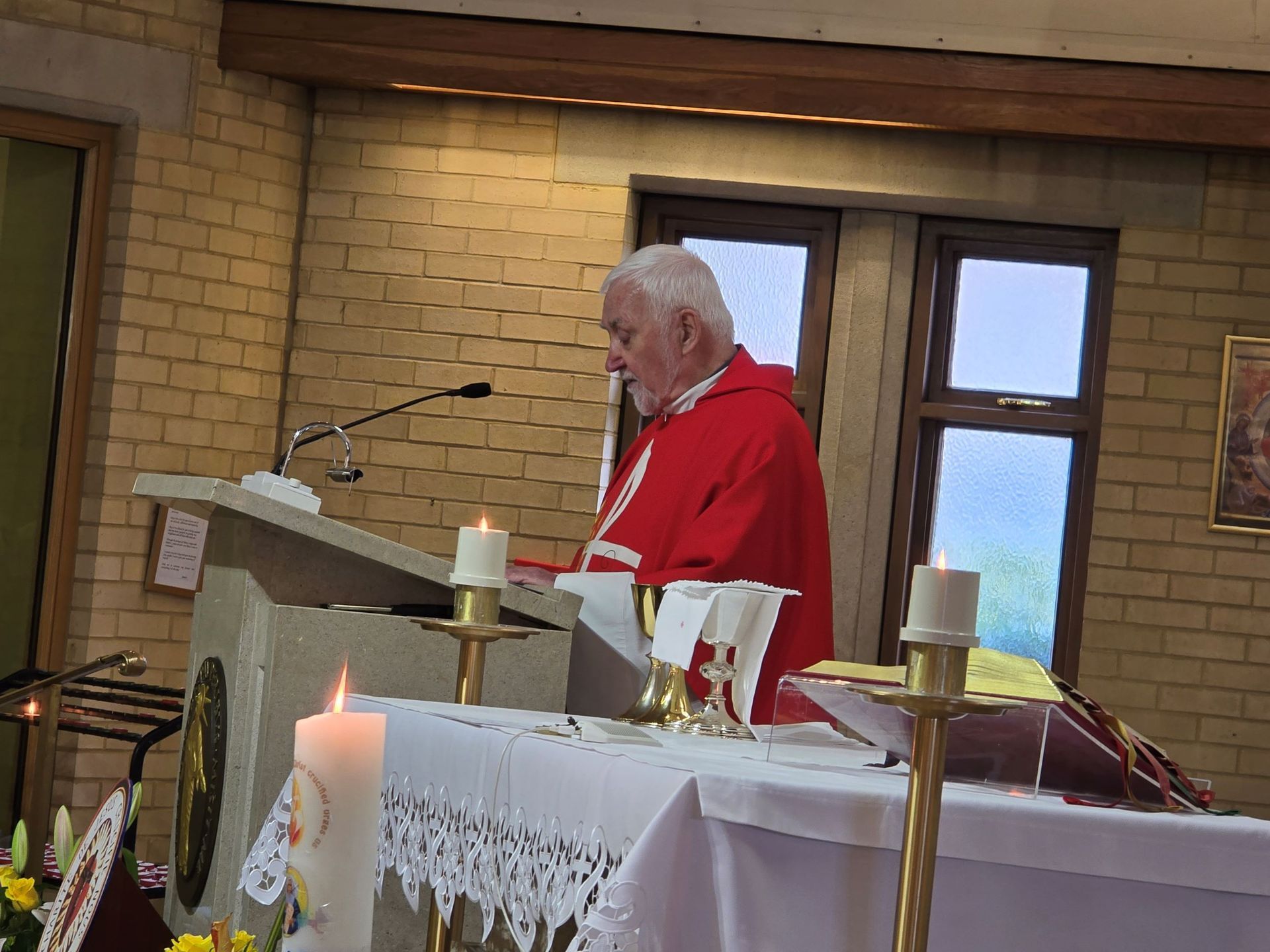 A man in a red robe is standing at a podium in a church.