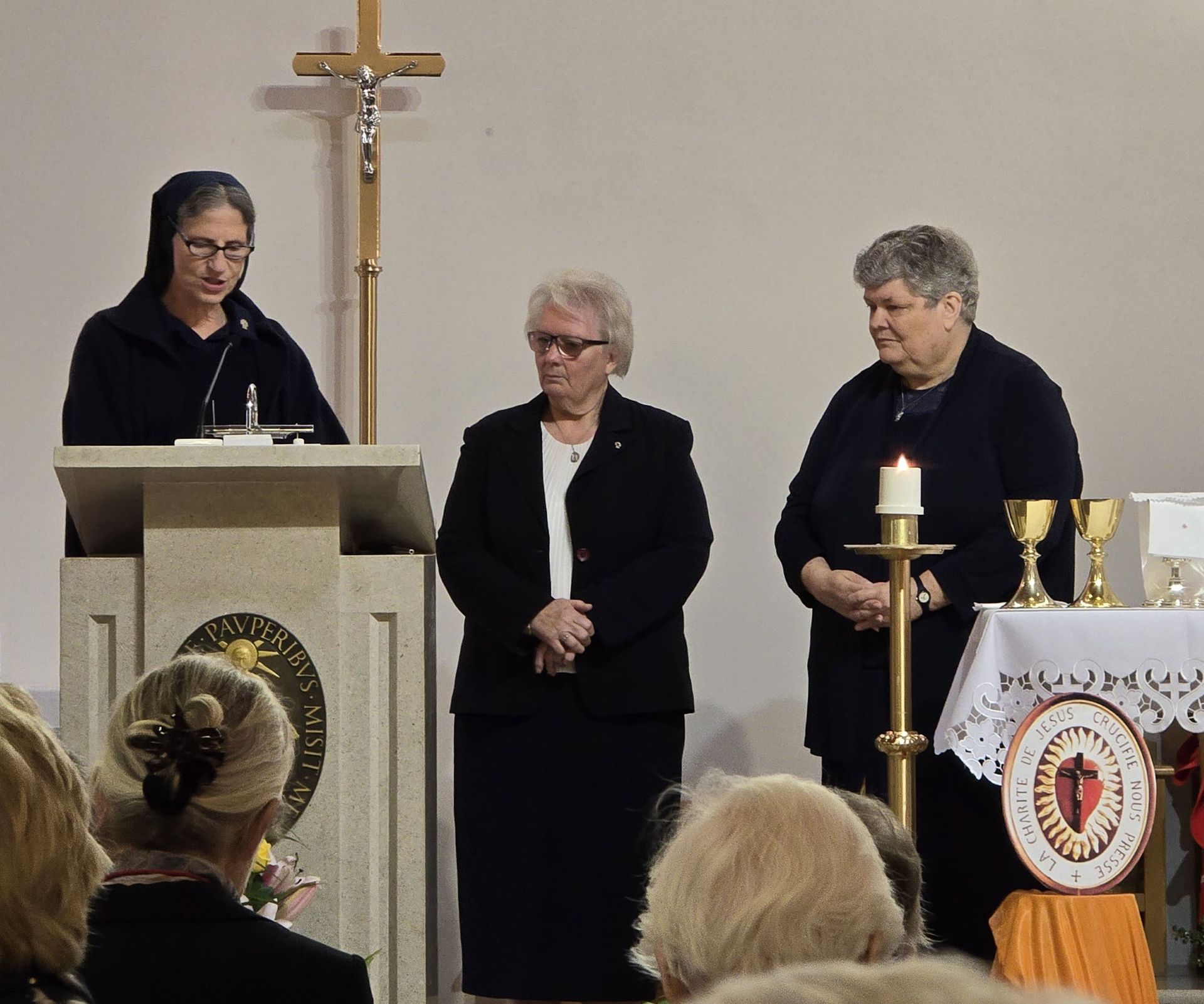A woman stands at a podium with a cross in the background
