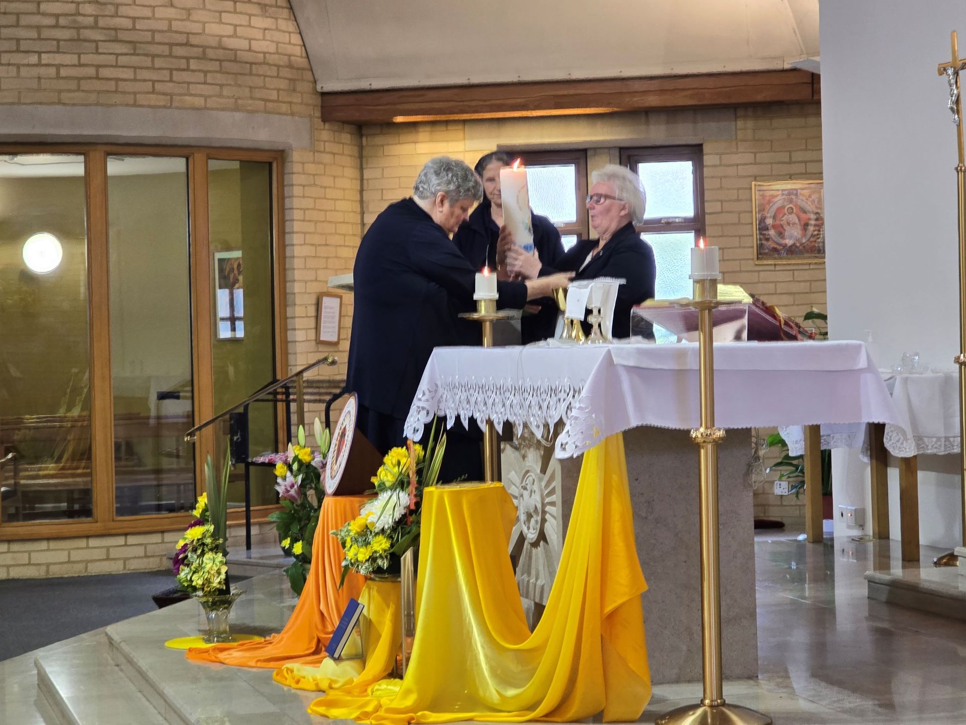 Two men are lighting candles at an altar in a church.