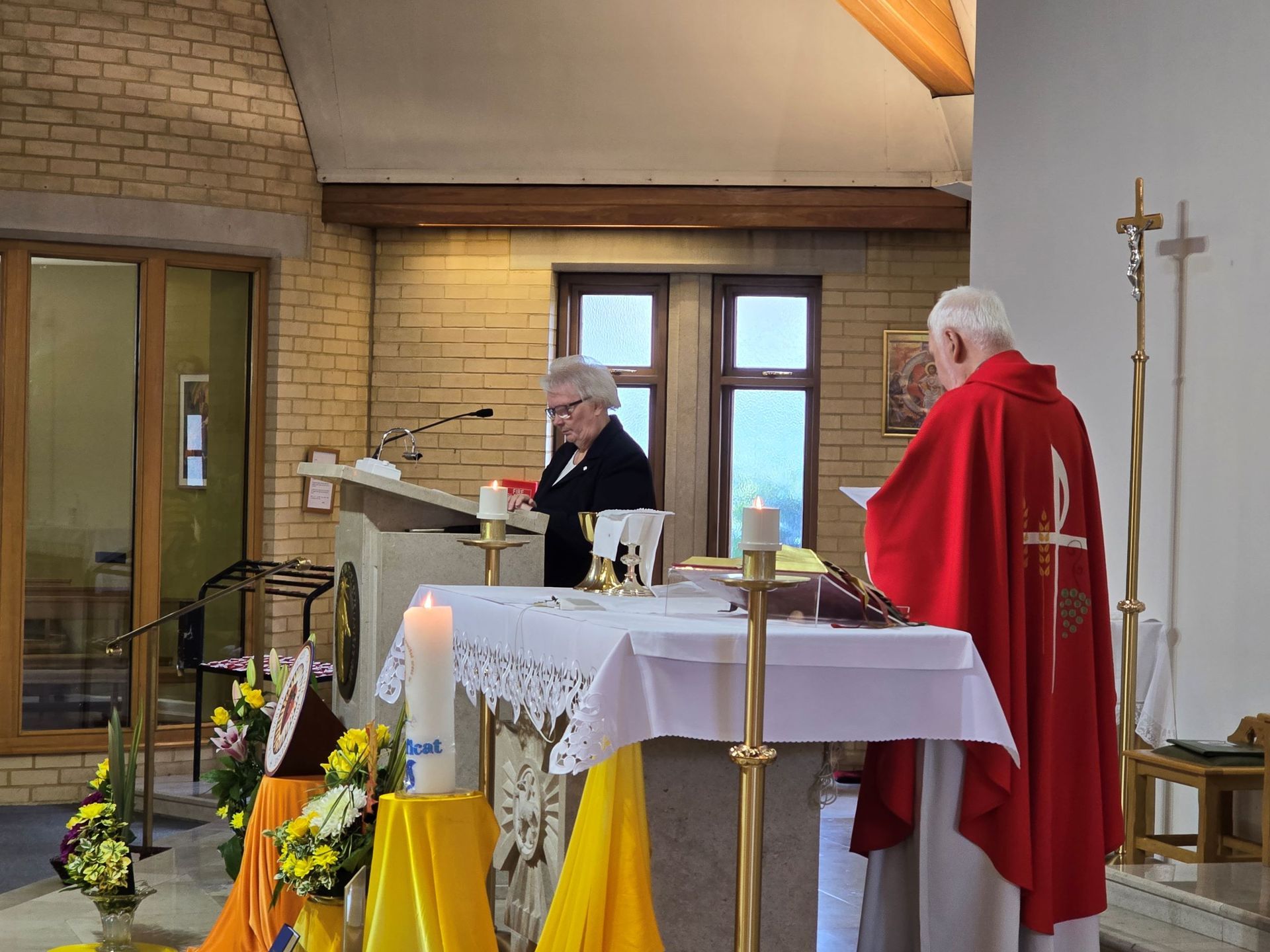A man in a red robe is standing at an altar in a church.