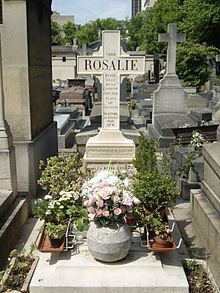 A grave with flowers and a cross that says rosalie