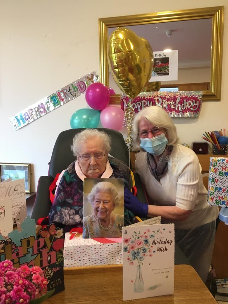 Two women are posing for a picture with an elderly woman in a chair.