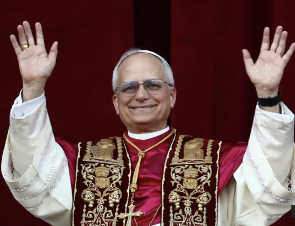 Pope with arms raised, wearing red and gold vestments, smiling on a balcony.