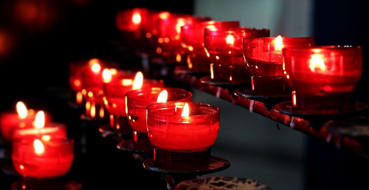 a row of red candles are lit up in a dark room .