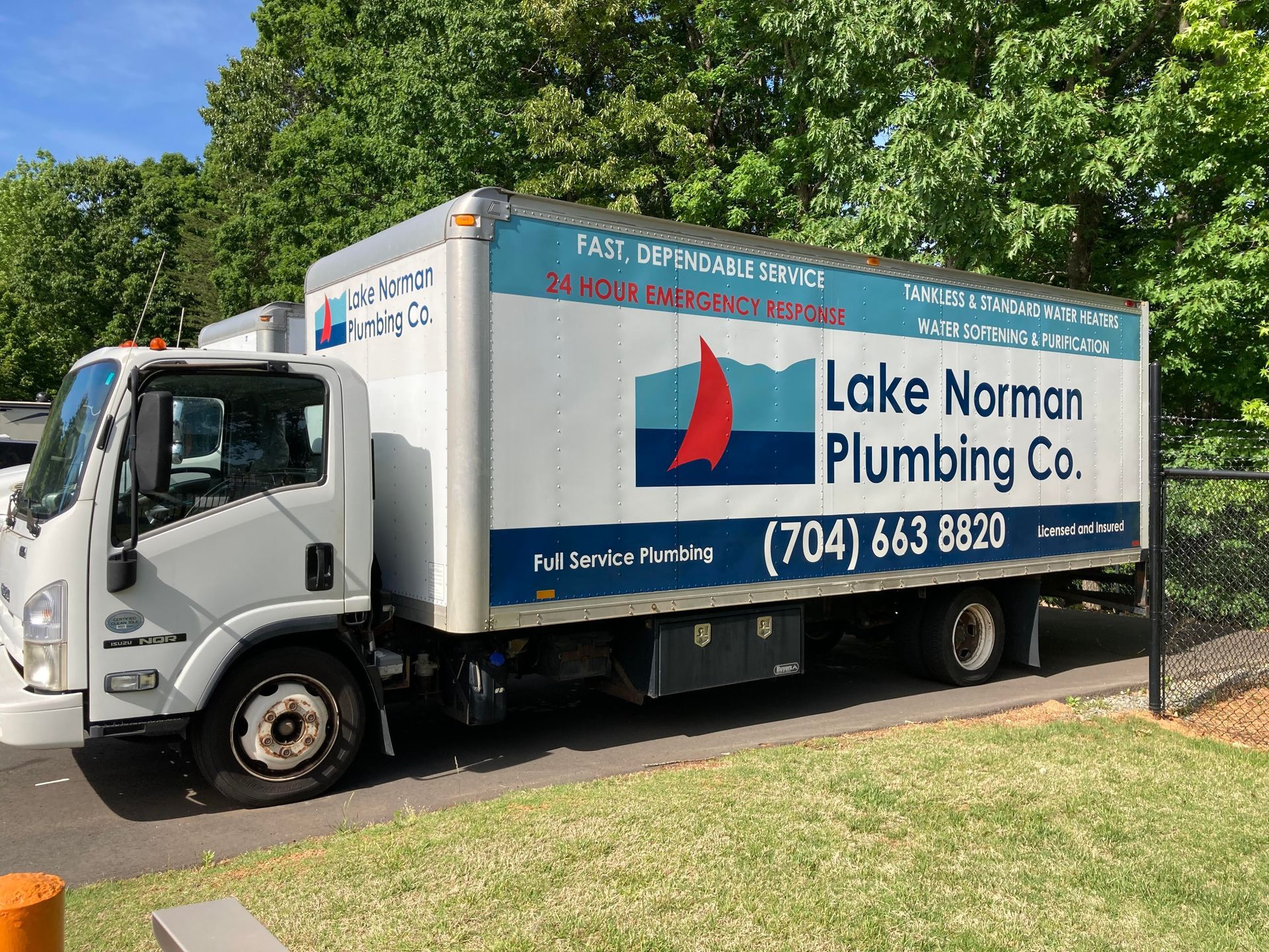 Lake Norman Plumbing Co. truck parked beside a grassy roadside, with trees in the background