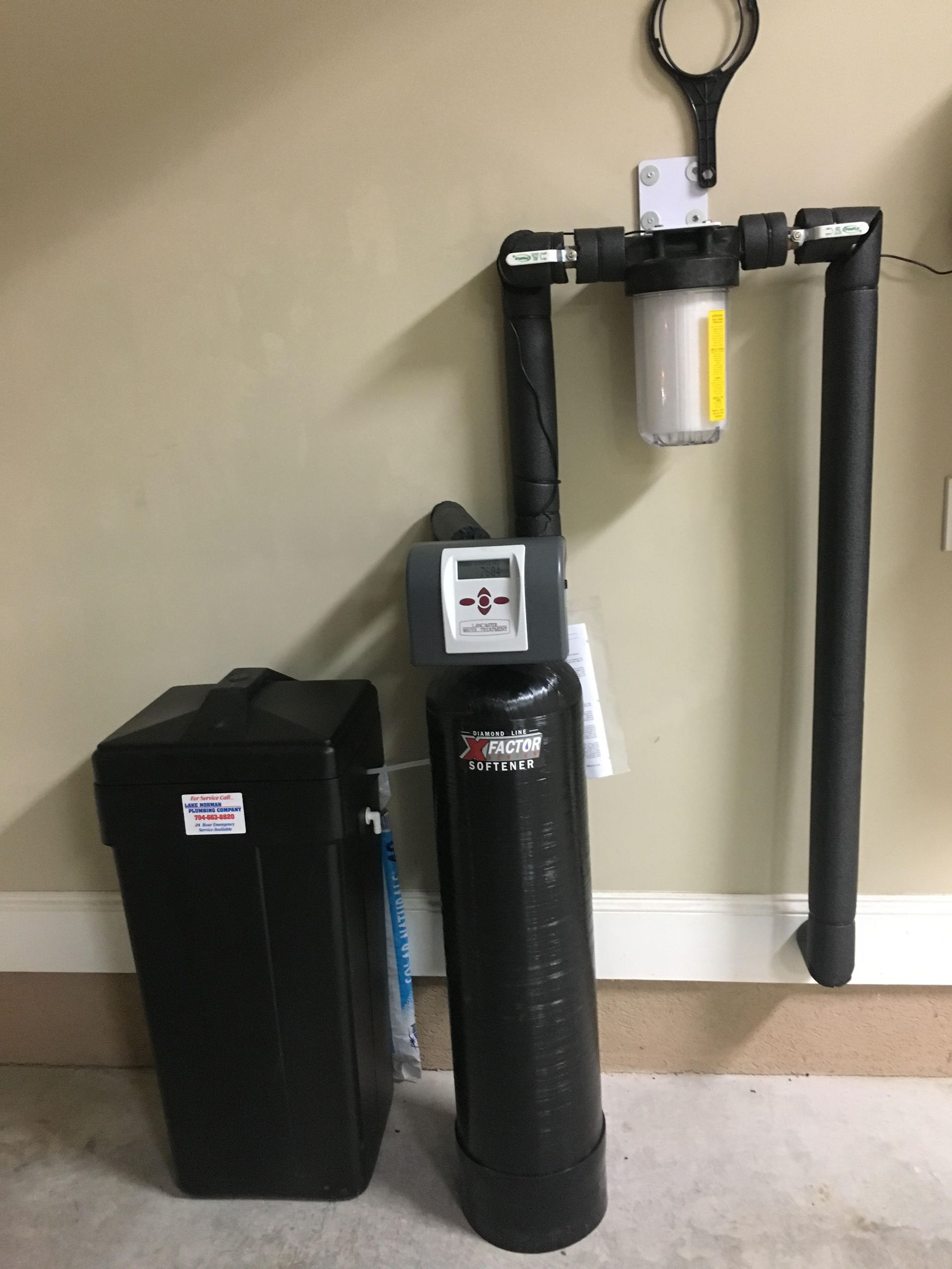 Fire extinguisher and black utility containers mounted on a beige wall in a hallway corner.