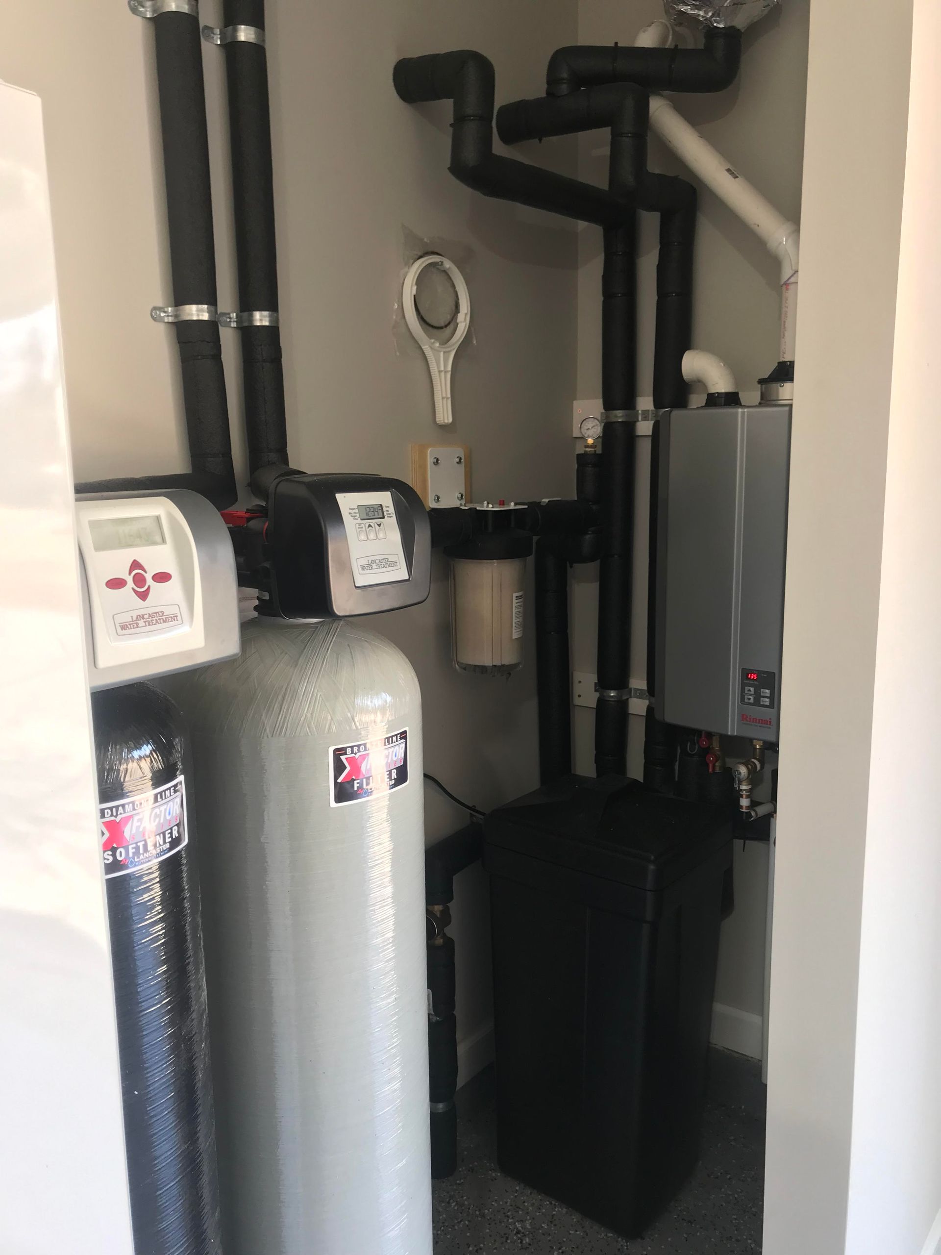 Water heater and HVAC equipment in a utility closet with exposed pipes and ductwork.