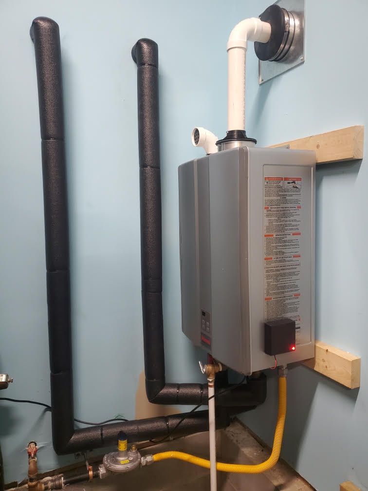 Wall-mounted tankless water heater with vent pipe, black pipes, and yellow gas line in a utility room