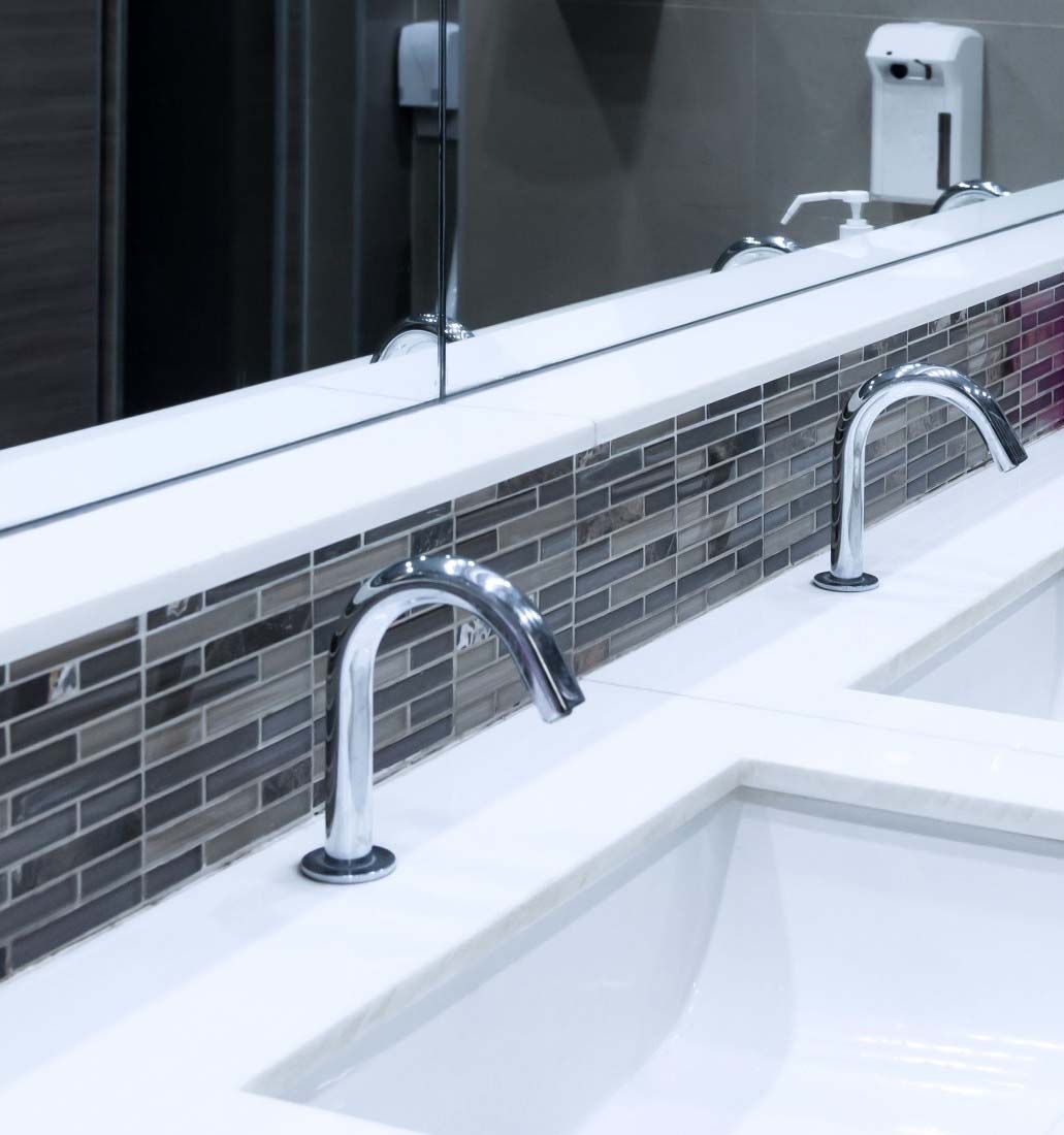 Modern bathroom sink with chrome faucets and gray tile backsplash
