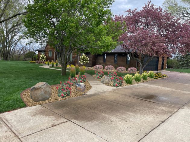 Single-story stone house with front walkway, ramp, and landscaped lawn.