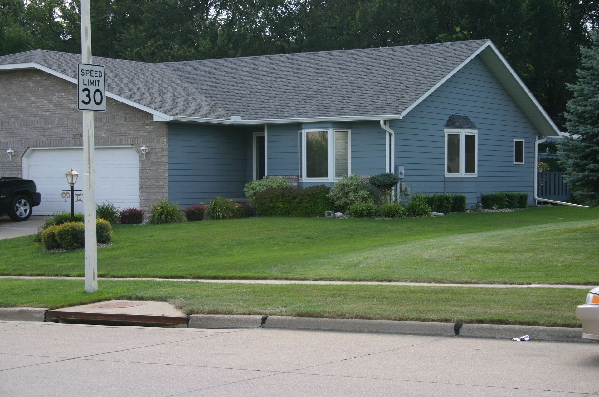 Suburban blue house with garage and a 30 mph sign by the street
