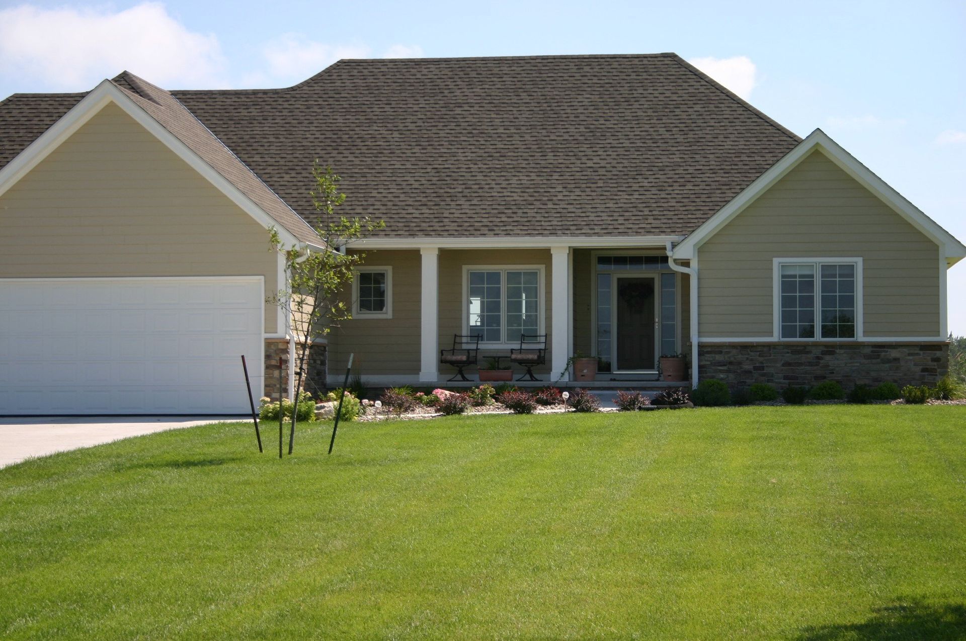 Suburban single-family house with a white garage, gray roof, and green lawn