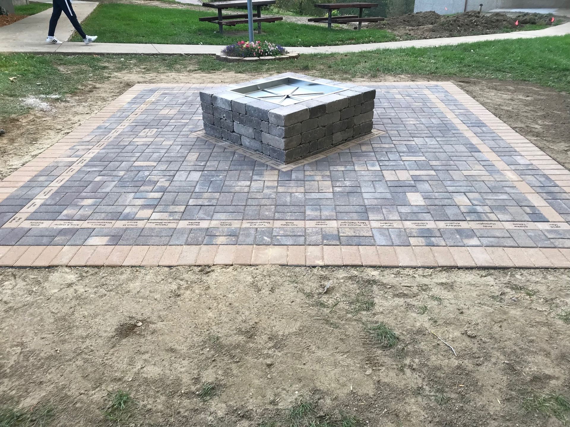 Brick plaza with a raised stone monument in a park area