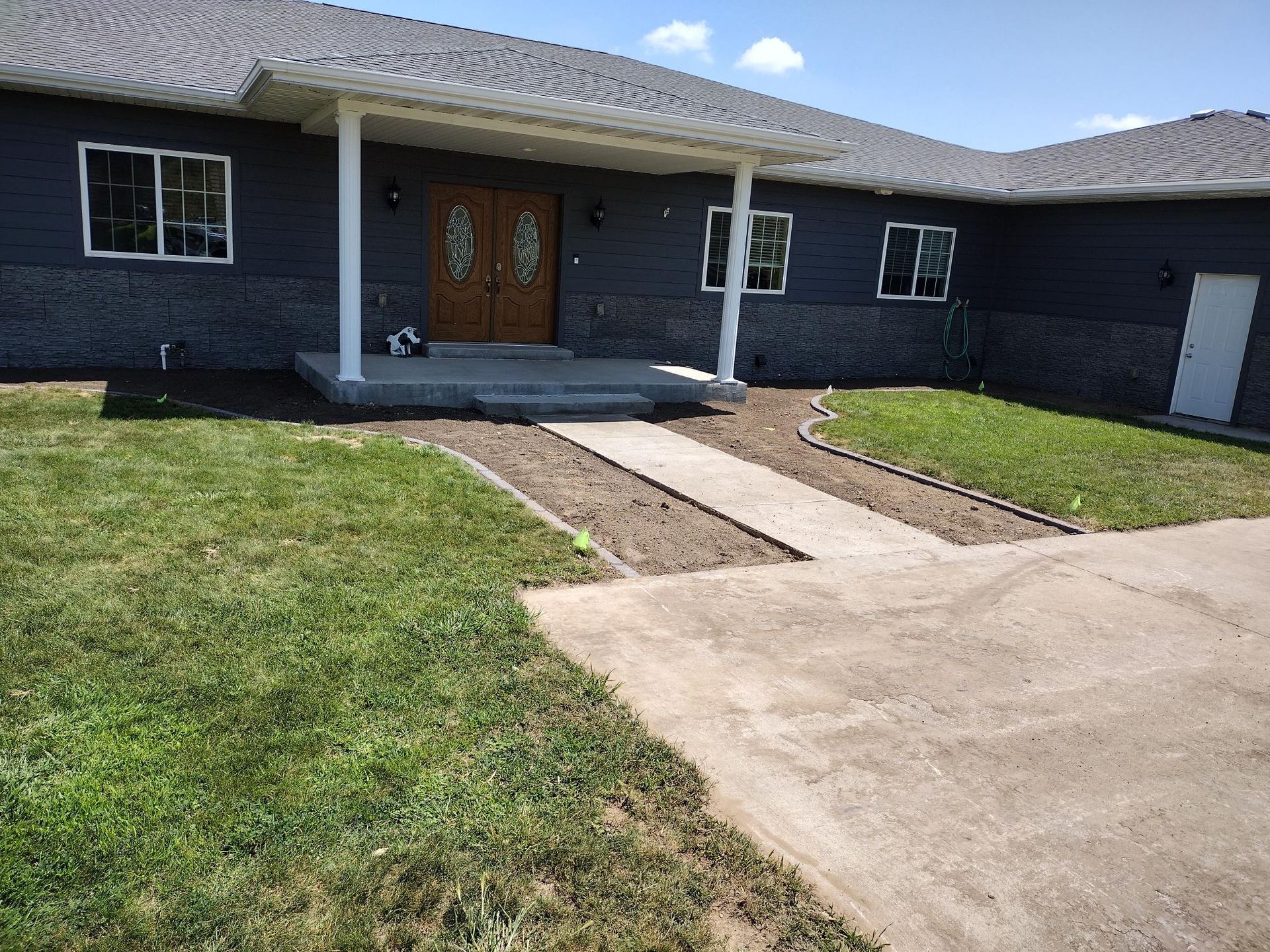 Single-story house with a covered porch, double front doors, and a concrete driveway leading to the entrance