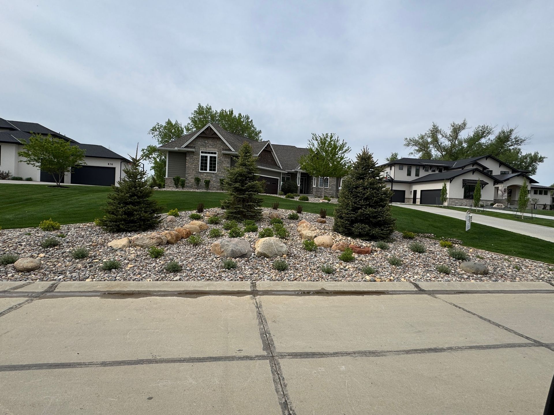 Suburban house with landscaped rock garden and driveway under a cloudy sky