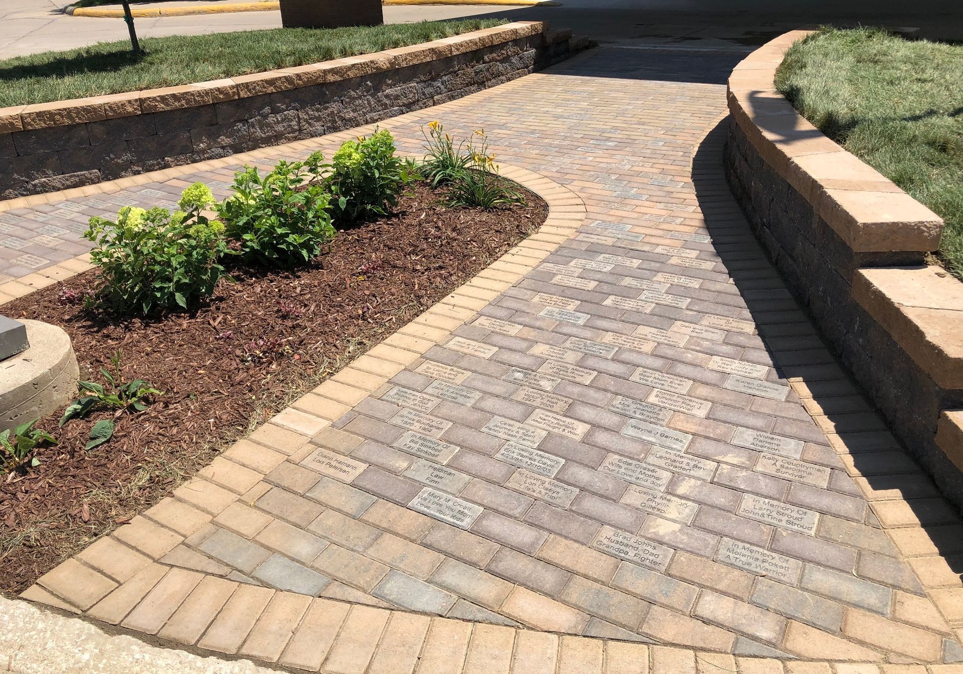 Curved brick walkway through landscaped garden beds on a sunny day