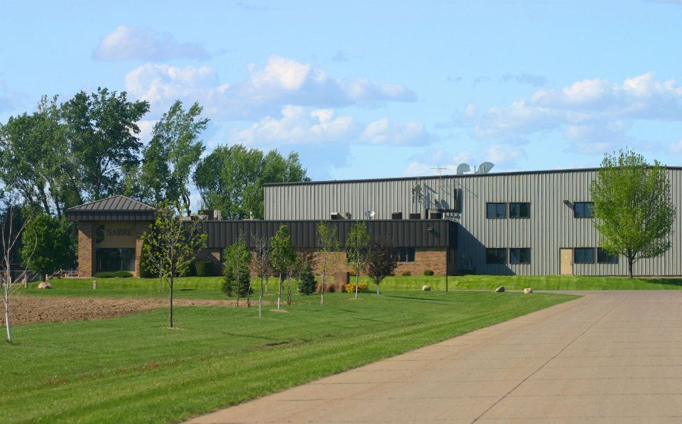 Modern building with gray siding beside a green lawn and sidewalk under a partly cloudy sky