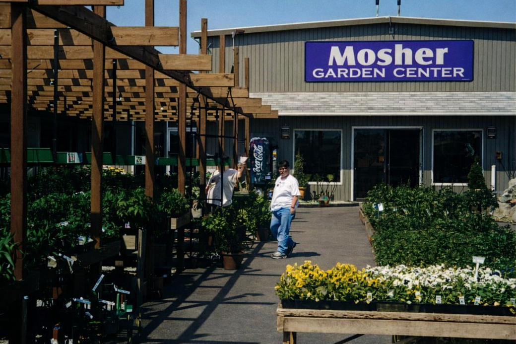 Mosher Garden Center storefront with outdoor plants and a person walking by
