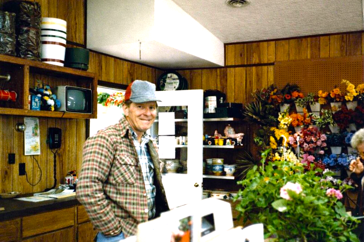 Man standing in a flower shop surrounded by colorful bouquets and wooden shelves