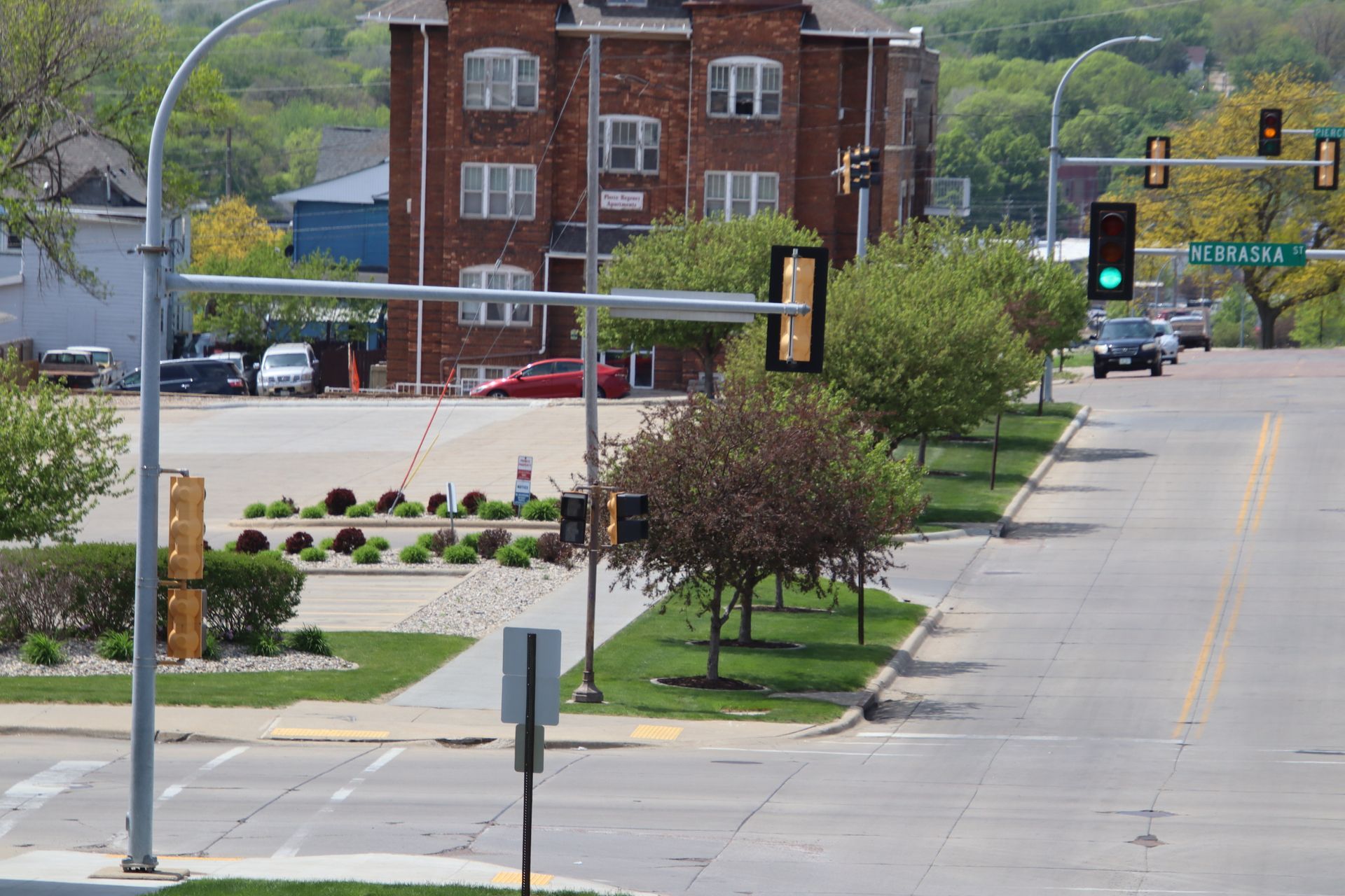 Empty city street intersection with traffic lights, brick buildings, and a landscaped median.