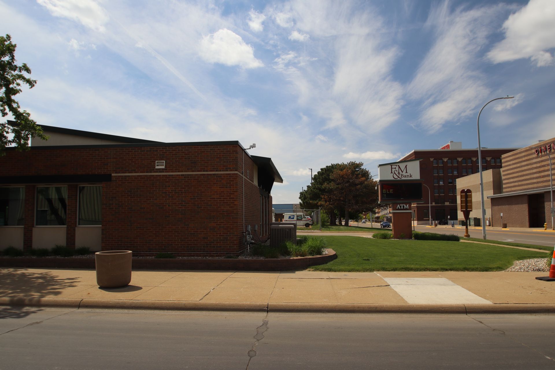 Street view of a brick campus building with a grassy courtyard under a partly cloudy sky