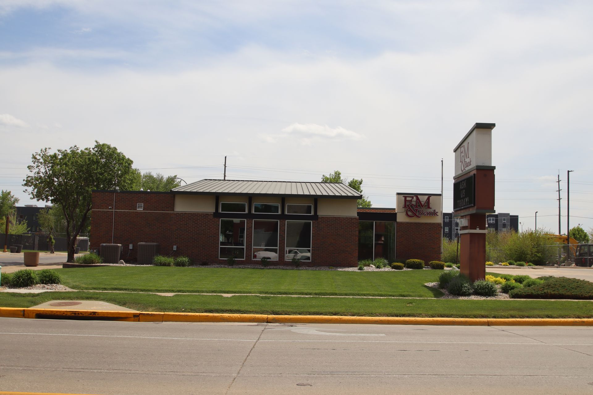 Low brick roadside building with a lawn and sign under a bright sky