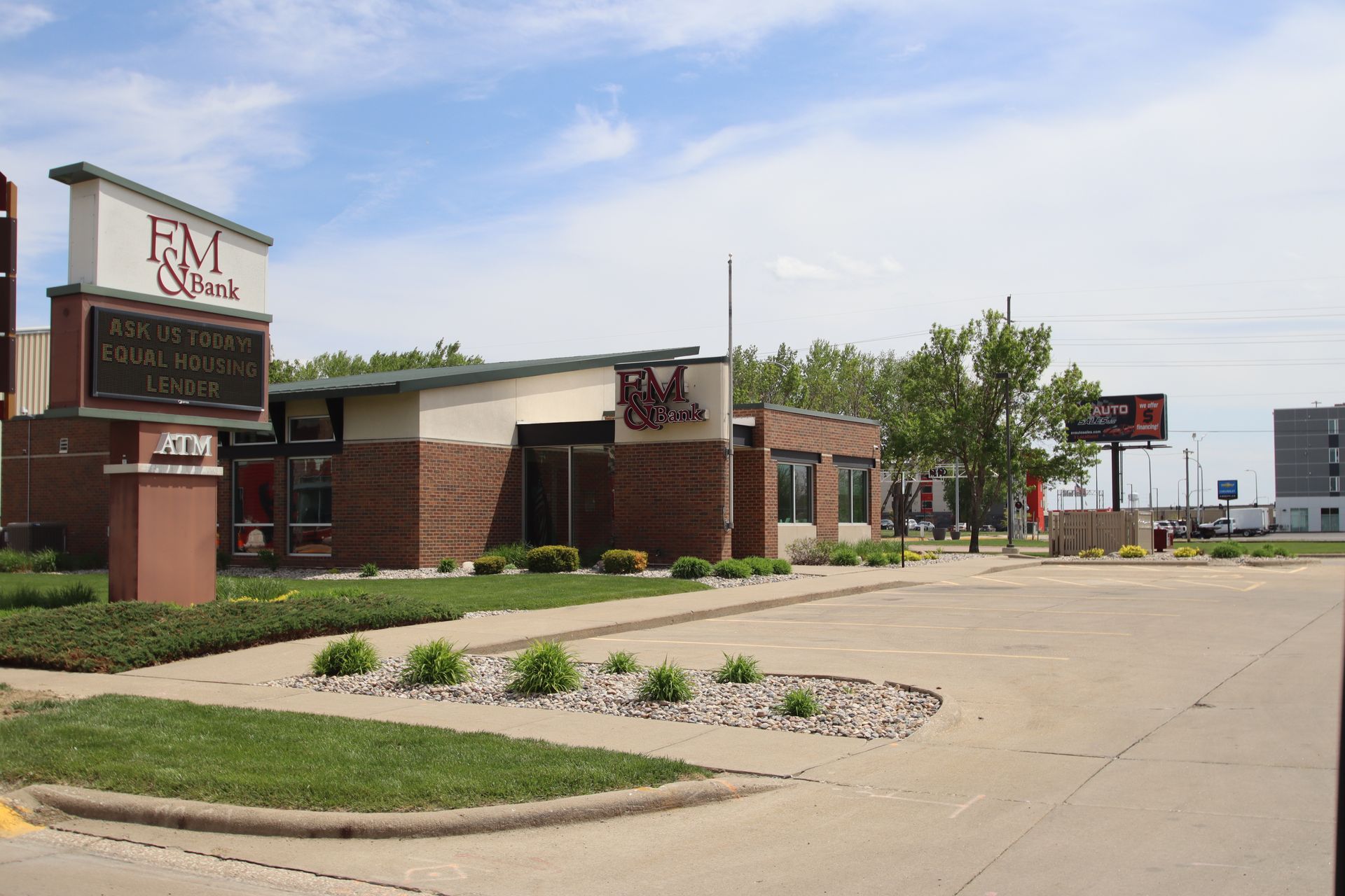 Street view of a brick restaurant and sign along a quiet roadside under a clear sky