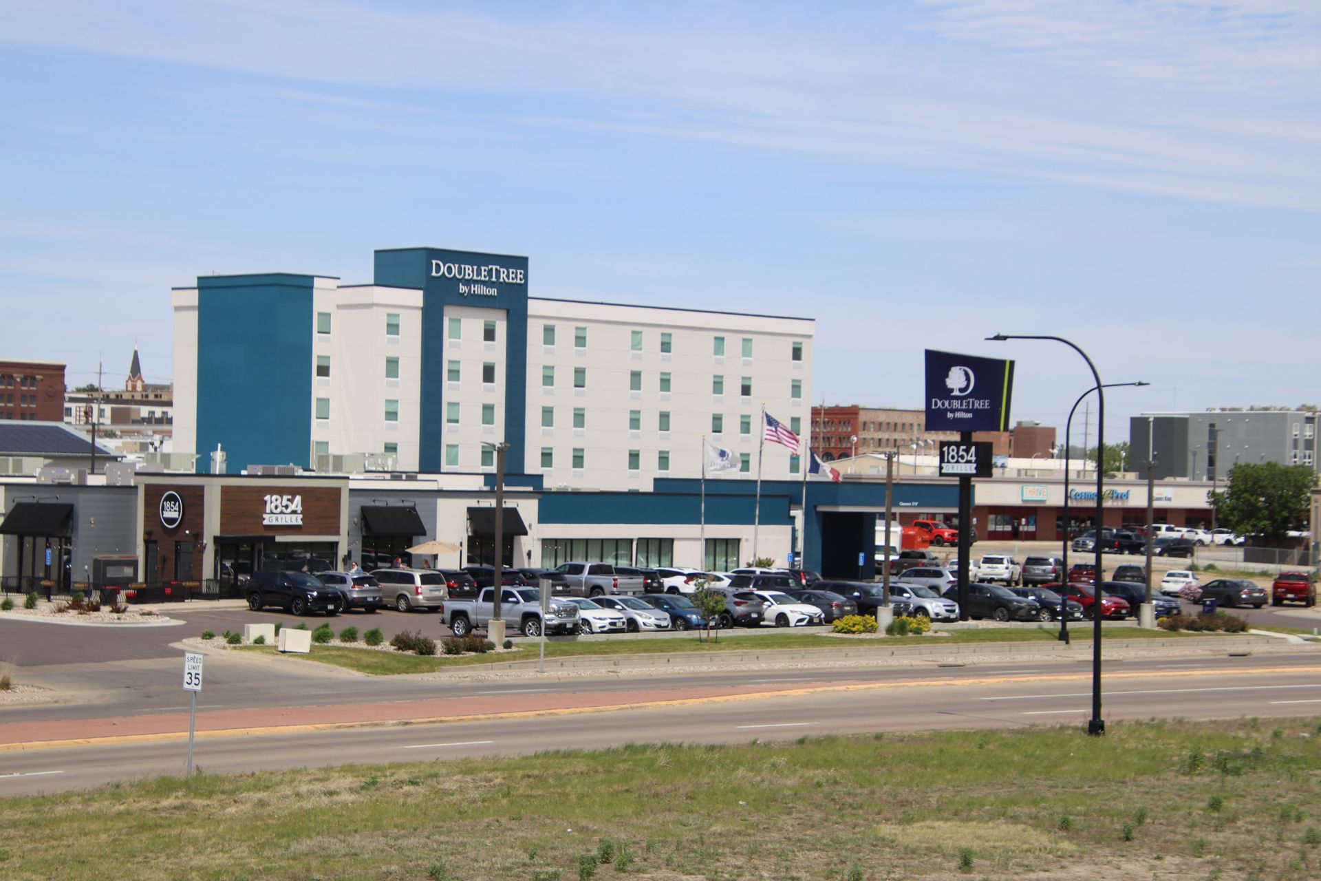 Hotel and busy parking lot beside a roadside commercial strip under a clear sky