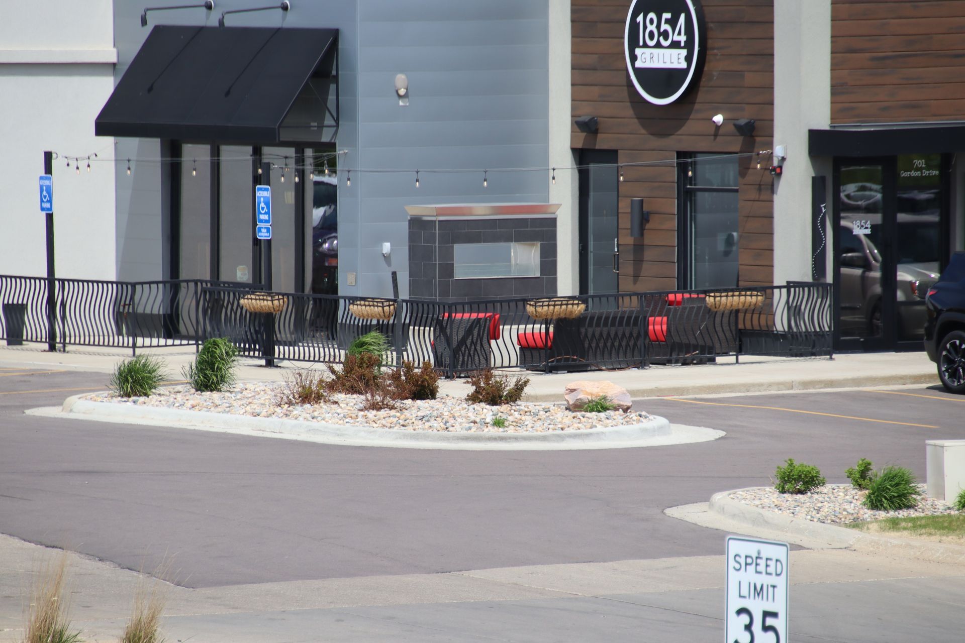 Storefront entrance with black awning, patio railing, and a sidewalk speed limit sign in front.