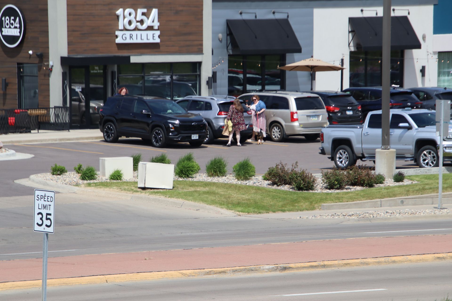 People loading bags into SUVs in front of 1854 Grille restaurant parking lot.