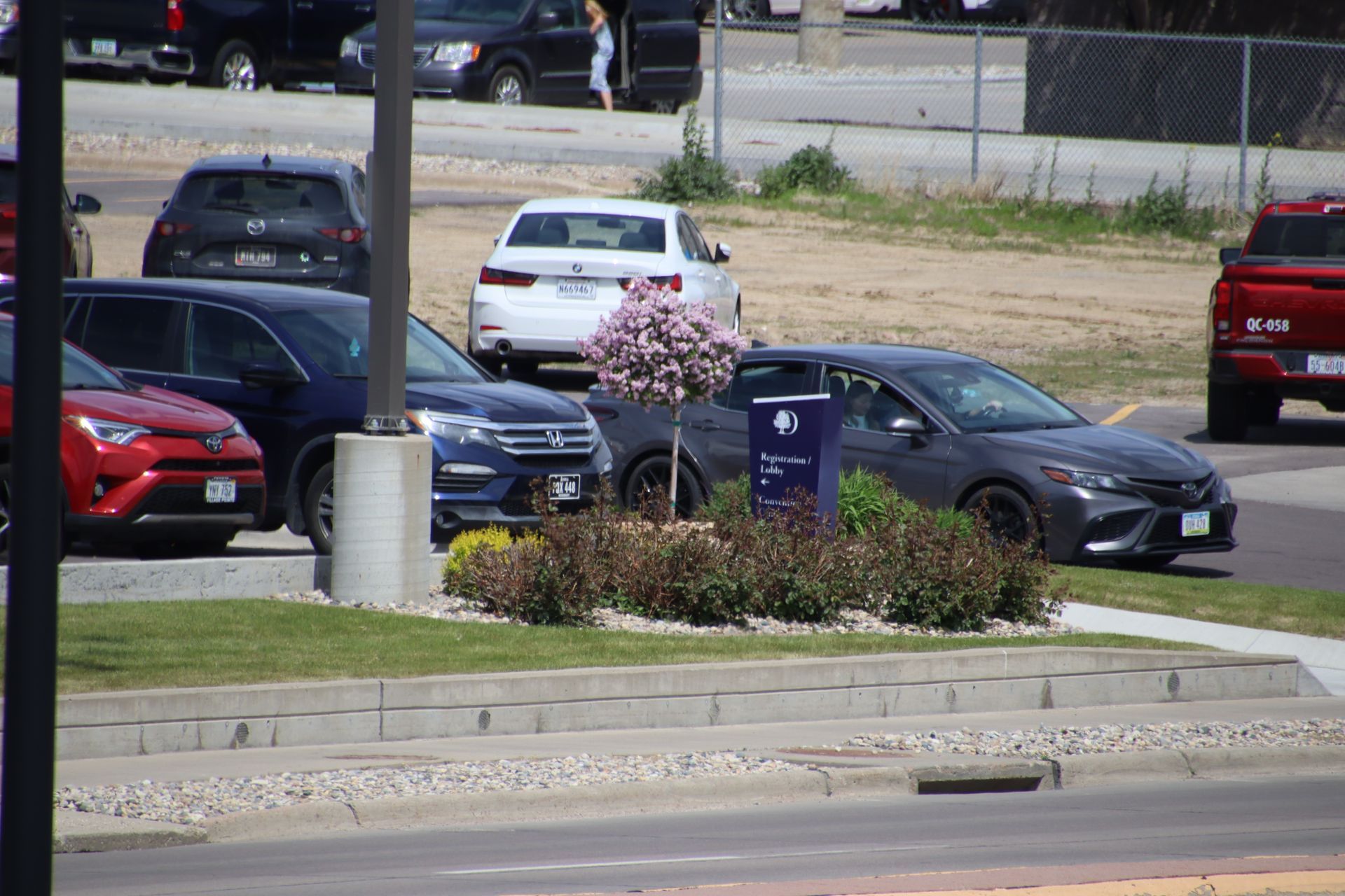 Parking lot with several parked cars beside a landscaped curb and road divider